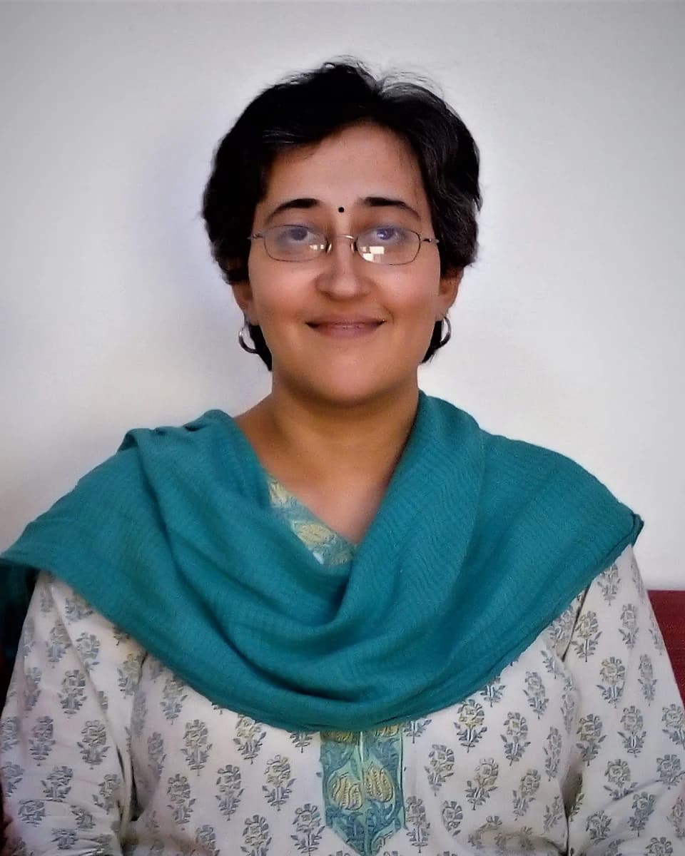 Atishi in spectacles and a teal scarf, smiling