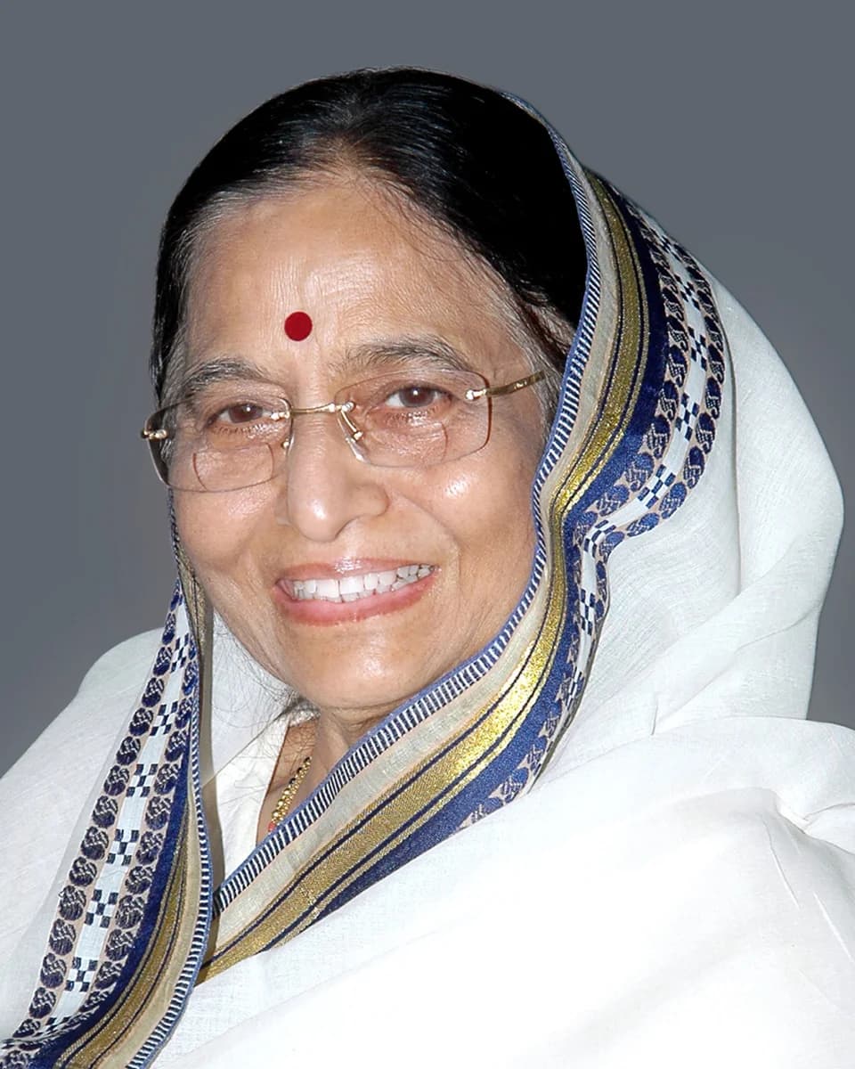 Pratibha Patil smiling, in a white sari with a blue and gold border