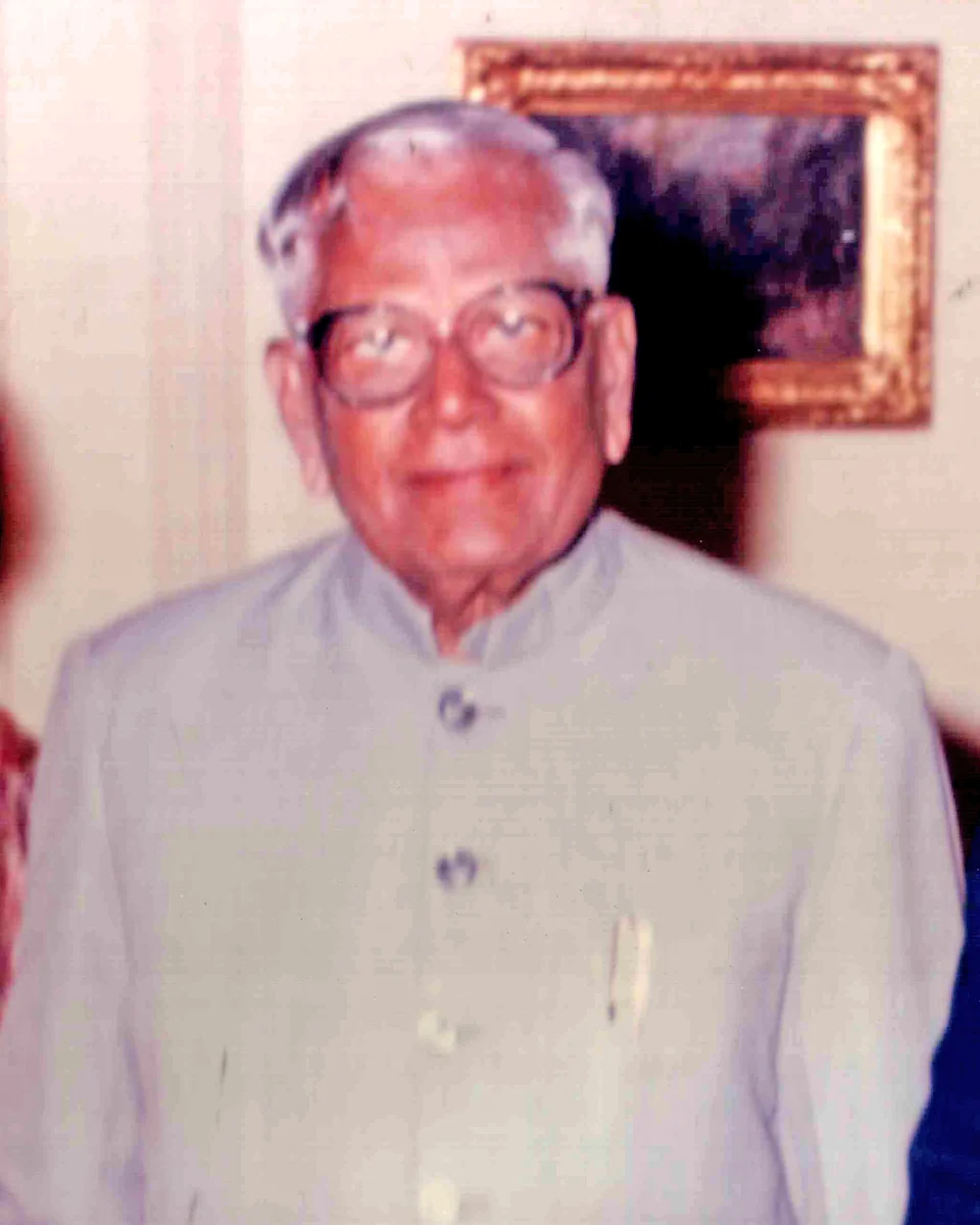R. Venkataraman in thick-framed glasses and a grey jacket, smiling, in a colour photograph