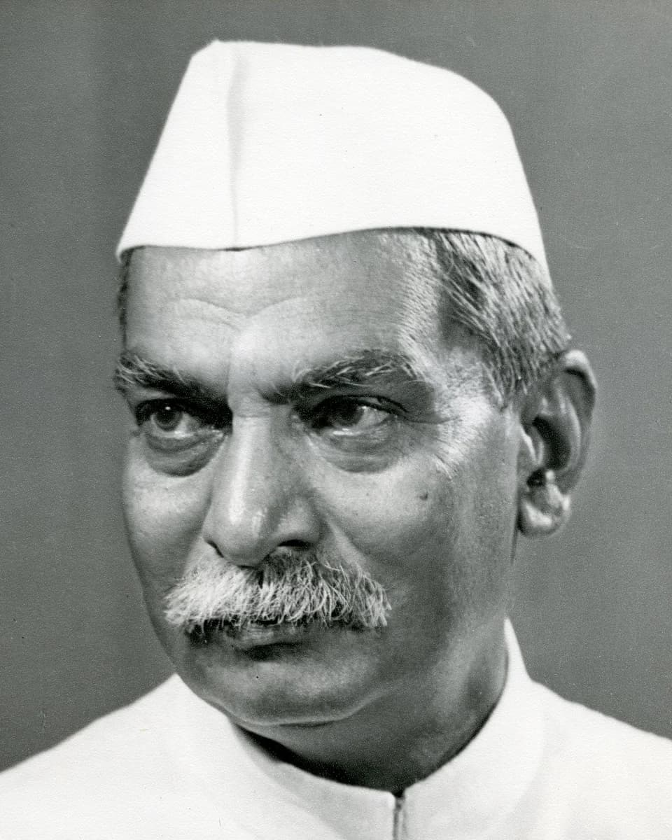 Rajendra Prasad in a white cap, looking to one side